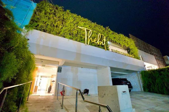 Fachada noturna iluminada da Clínica Thebit